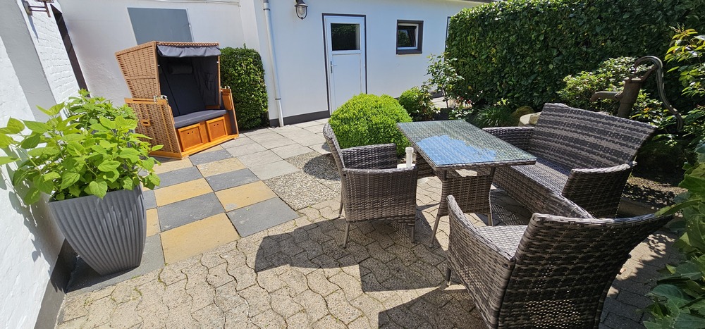 Sonnige Terrasse mit Strandkorb und Gartenmöbeln